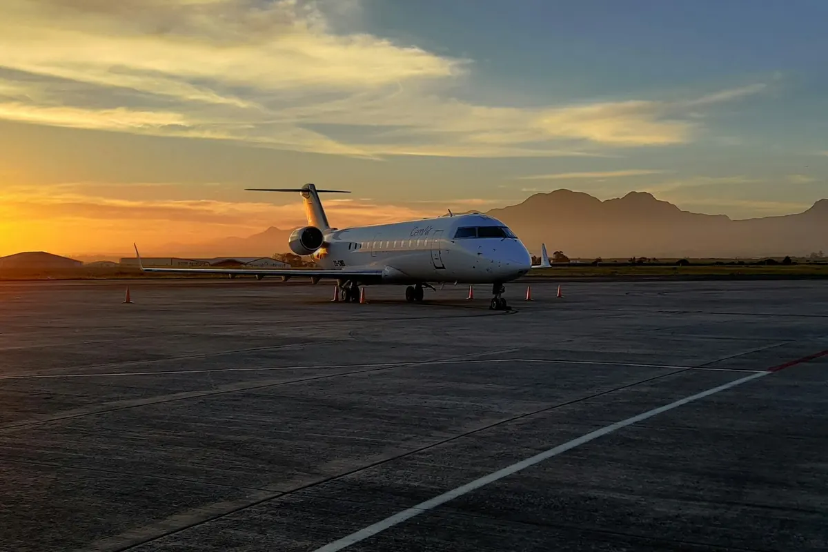 Super-midsize business jet on a ramp at sunset with mountains behind