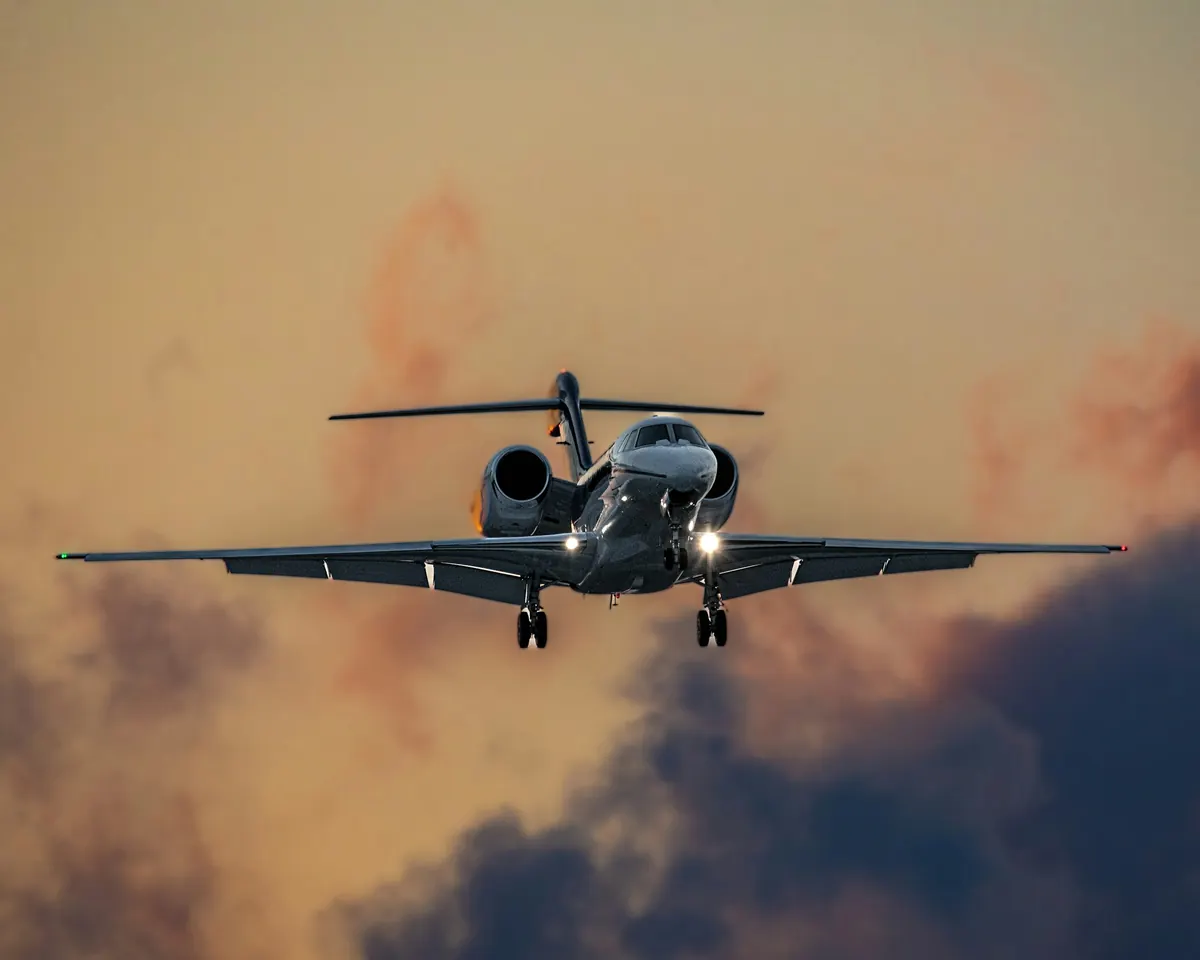 Business jet on final approach with landing gear down, framed by evening cloud