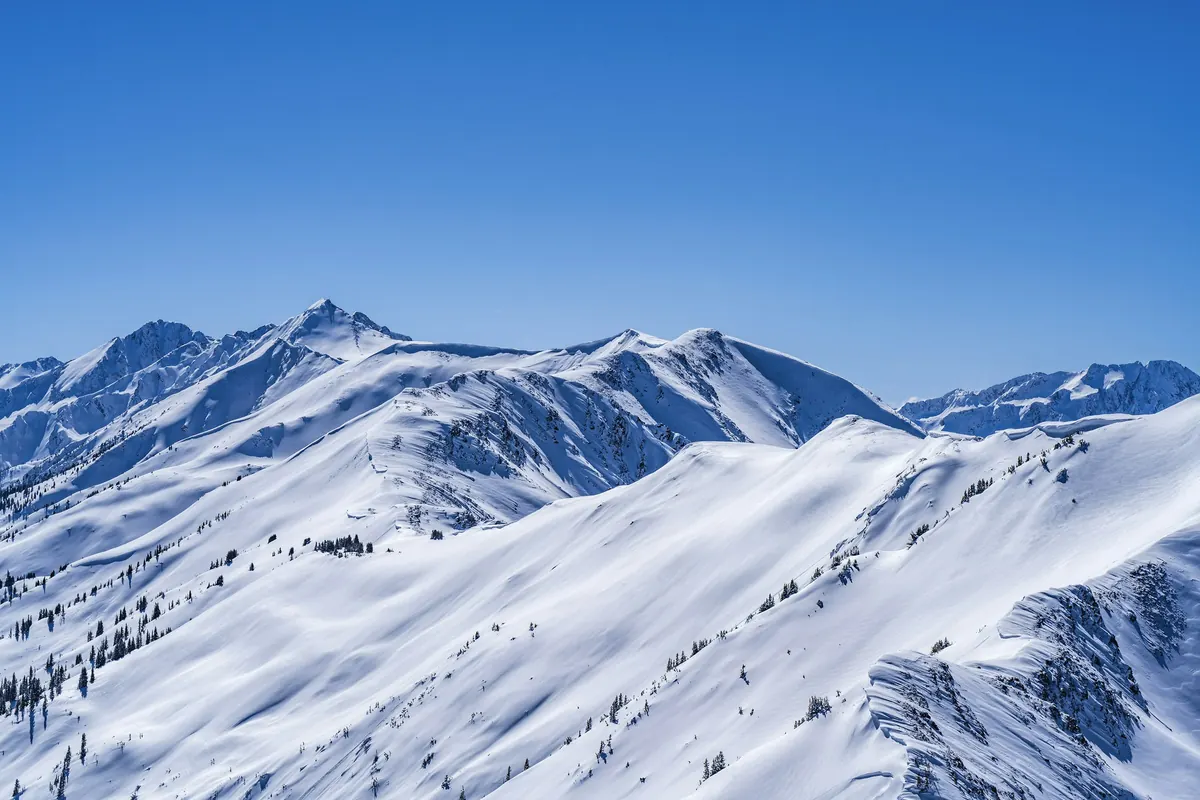 Snow-covered mountain peaks under a deep blue winter sky