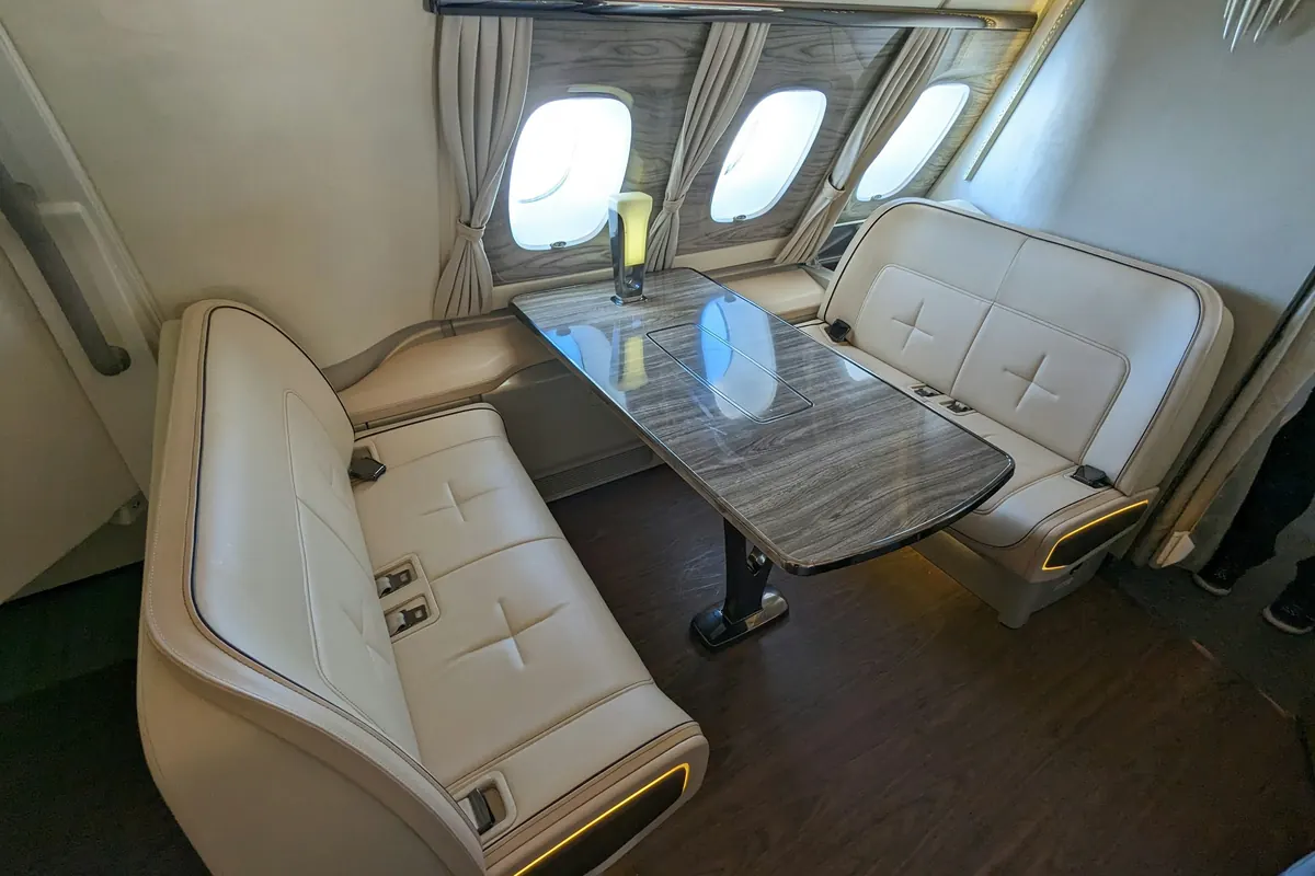 Business jet cabin with club seating, a side-facing divan and a polished table