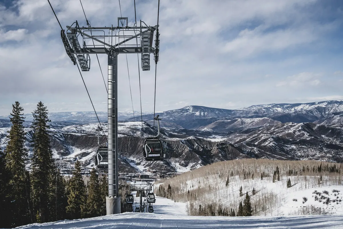 Chairlift towers above snowy slopes with mountain views near Aspen