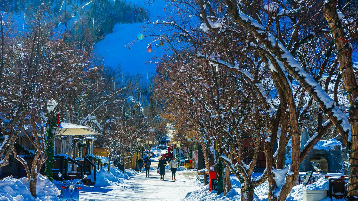 Snow-lined pedestrian street in downtown Aspen with bare trees in winter